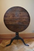 A Georgian country oak tilt top table on tripod cabriole supports. H.66 Dia.70cm (H.104cm tilted)