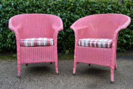 A pair of Lloyd Loom vintage wicker conservatory armchairs with fitted seats.