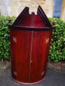 A Georgian mahogany bow fronted hanging corner cupboard. H.136 W.79 D.58cm