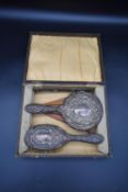 A sterling silver W Broadway & Co repousse work cased brush & comb set with stylised floral and