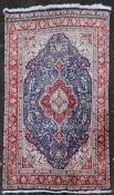 A Persian Keshan carpet with central floral medallion on sapphire ground within foliate multiple