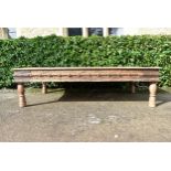 A large Indian teak carved and metal bound low table.