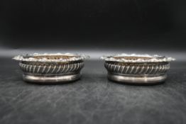 A pair of Georgian silver and oak wine coasters, stylised in classical form with foliate decoration.