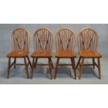 A set of four stained pine Windsor wheelback dining chairs.