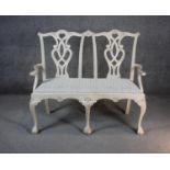 A Chippendale style painted twin chair back settee with drop in seat on carved cabriole ball and