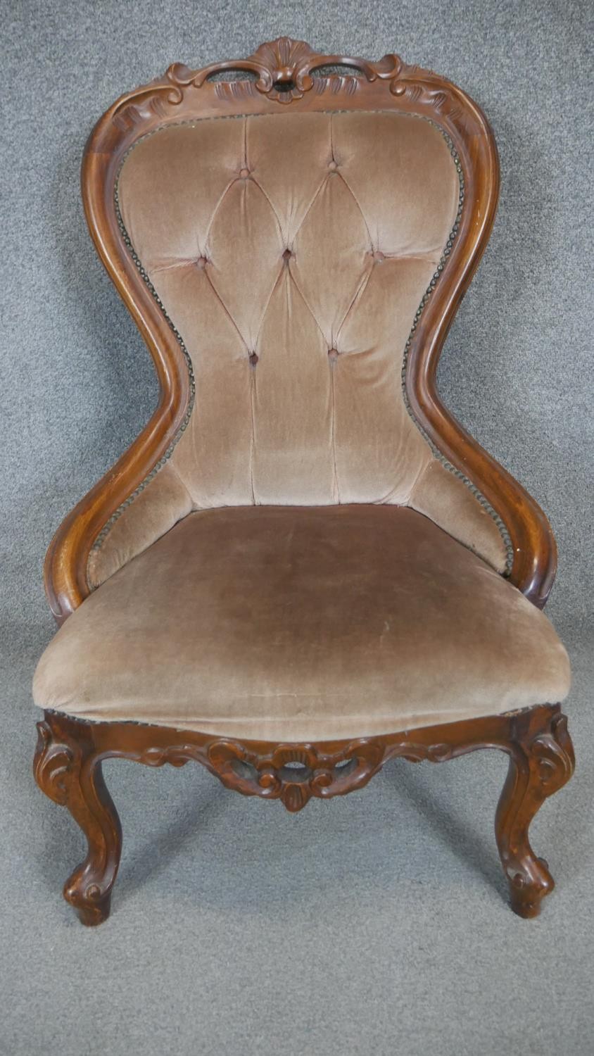 A Victorian style carved frame nursing chair on cabriole supports.