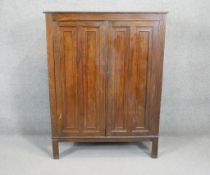 A mid century vintage oak wardrobe with panel doors enclosing fitted interior on square supports.