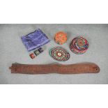 An embroidered silk textile along with a leather belt and tribal straw coasters and place mats. L.67