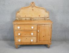 A Victorian pine sideboard with carved and shaped back above cupboard and drawers on turned baluster