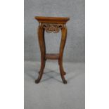 An Eastern hardwood jardiniere stand with carved frieze on cabriole supports united by an undertier.