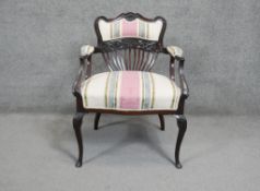 A Victorian carved mahogany armchair in striped upholstery on slender cabriole supports.