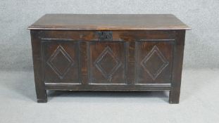 A 17th century oak coffer with lozenge carved panels raised on stile supports. H.54 W.104 D.49cm