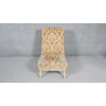 A vintage nursing chair in cut floral fabric on splay supports.