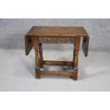 A small mid century oak Jacobean style twin drop flap occasional table with carved frieze on