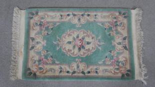 A small Chinese rug with floral central medallion on a jade ground with complementary borders. L.100