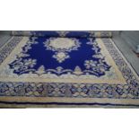 A Persian Kirkman carpet with central floral medallion on a sapphire ground within floral borders