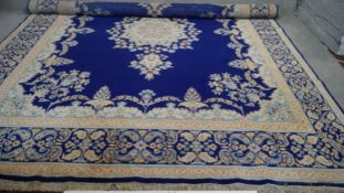 A Persian Kirkman carpet with central floral medallion on a sapphire ground within floral borders