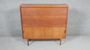 A 1960's vintage teak bureau with fall front revealing fitted interior on shaped supports, maker's