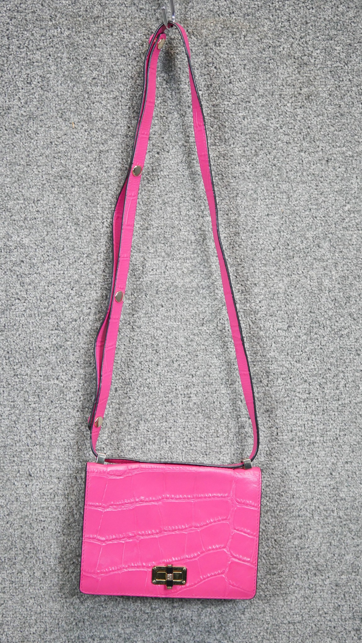 A neon pink Diane Von Furstenberg embossed leather crossbody bag. Brass Hardware and gilded name.