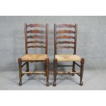 A pair of oak Lancashire style ladder back dining chairs with woven rush seats.