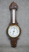 A late 19th century carved oak banjo barometer with white enamel dials and foliate design. H.84 W.