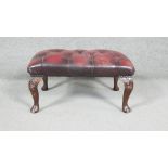 A Georgian style stool in deep buttoned leather upholstery on cabriole supports. H.20 W.65 D.43cm