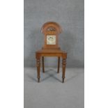 A late 19th century oak hall chair with inset Mintons tile to the back above panel seat on turned