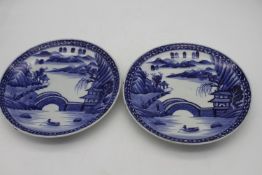 A pair of Japanese Arita style porcelain blue and white chargers hand painted with a landscape