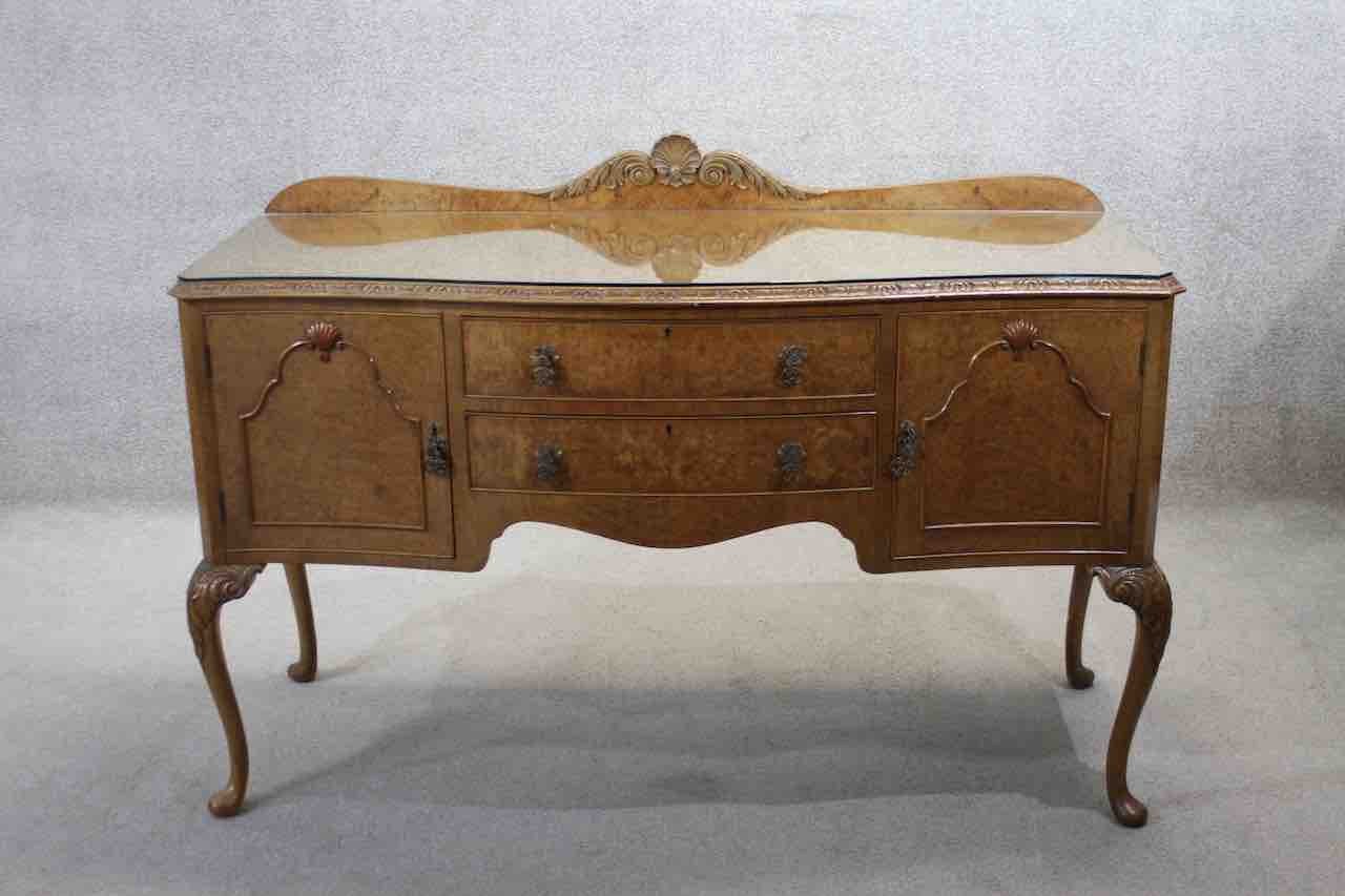 A mid century burr walnut Epstein sideboard with central drawers flanked by cupboards on carved