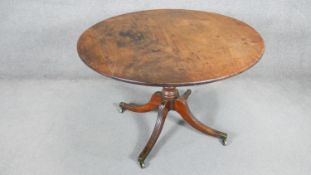 An early 19th century mahogany tilt top table on ring turned column and quadruped swept supports.