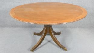 A Georgian style mahogany and crossbanded dining table on quadruped swept supports terminating in