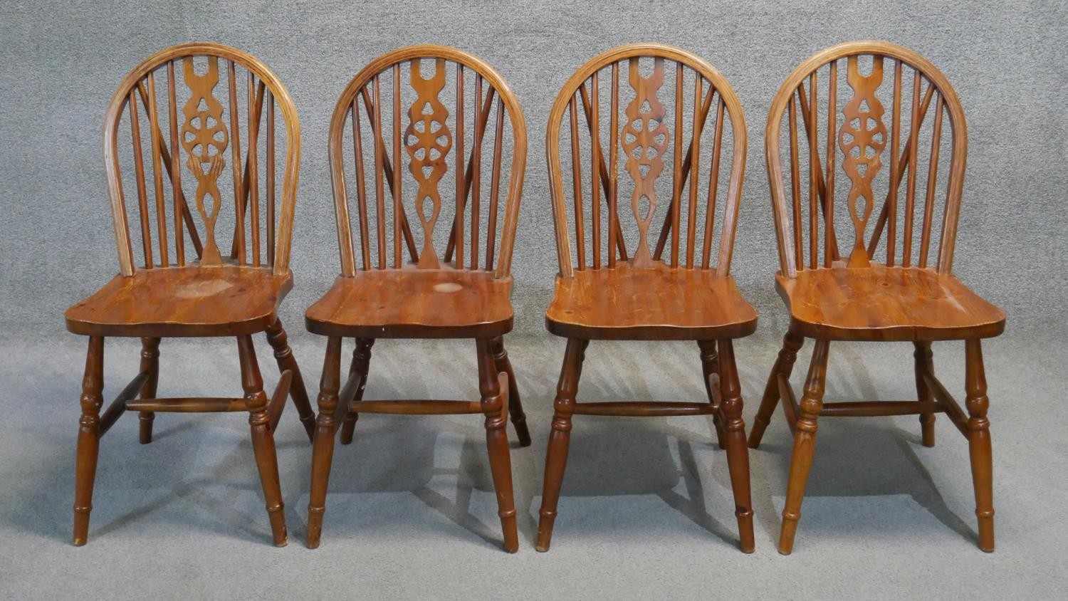 A set of four stained pine Windsor wheelback dining chairs.