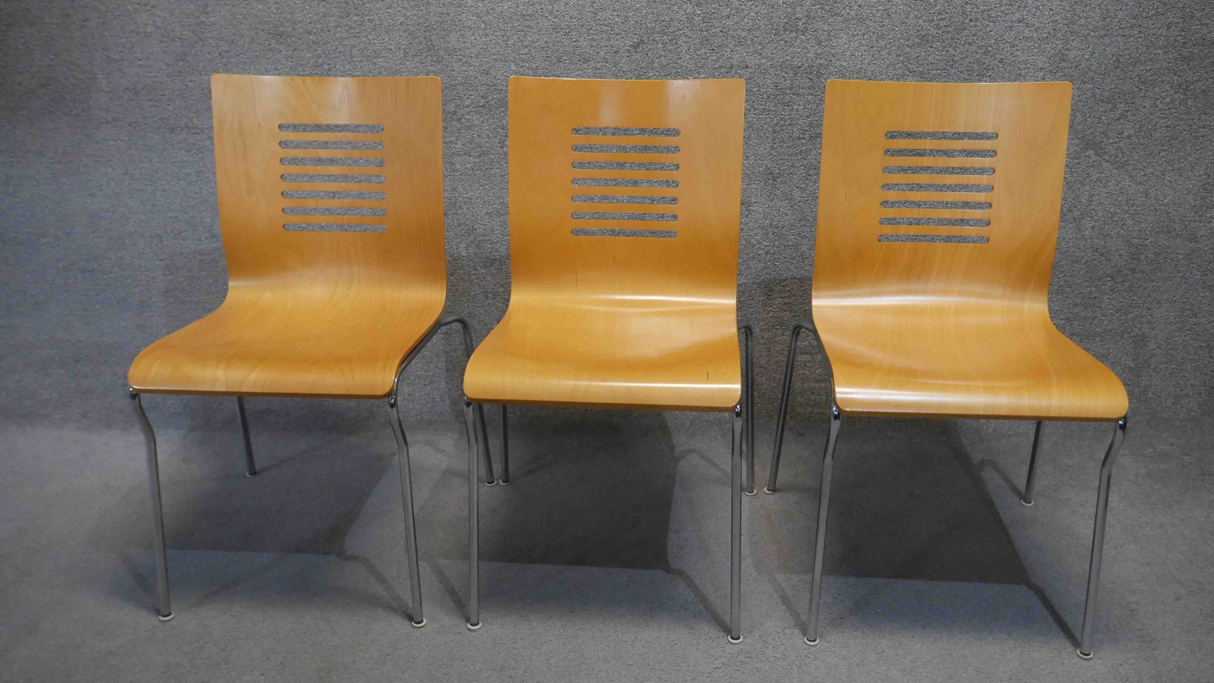 Three contemporary laminated dining chairs on chrome frames.