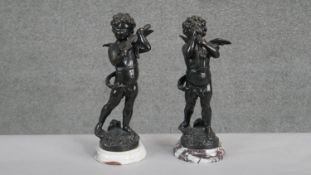 A pair of spelter figures of winged putti, one playing the violin and one playing the saxophone,