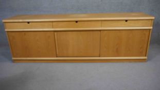 A Danish light teak sideboard fitted with drawers and sliding doors on plinth base by Mogens Kold.