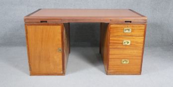 A mid century teak pedestal desk with pull out slides and inset brass military style handles,