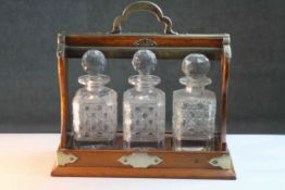 An oak tantalus with brass bound detailing, enclosing three cut crystal decanters, each with