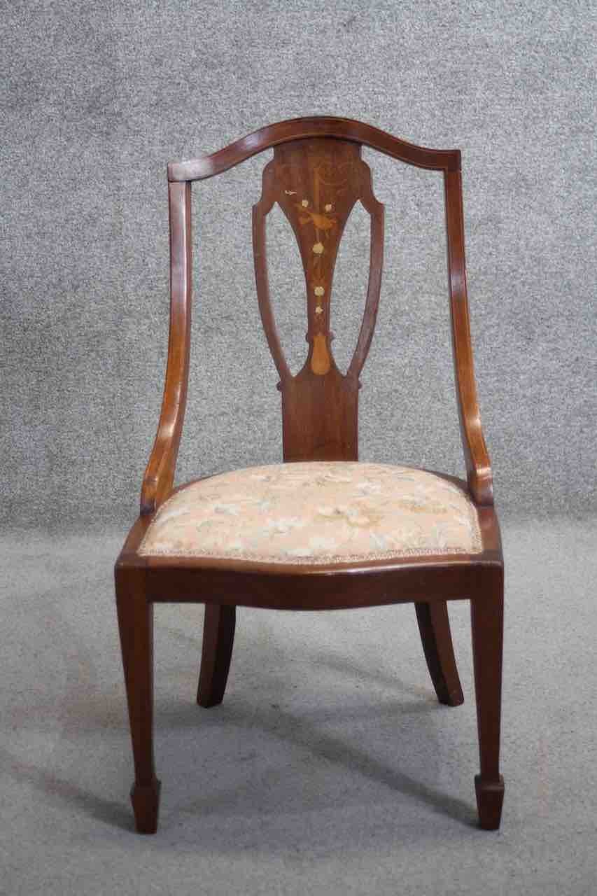 An Edwardian mahogany bedroom chair with scrolling ribbon and foliate inlay on tapering supports