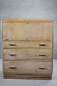 A mid century vintage limed oak secretaire chest with fall front revealing fitted interior above