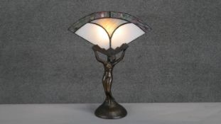 An Art Deco style bronze effect lamp of a female figure with stained glass fan shade. H.38 W.31cm