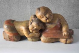 A pair of carved painted Chinese good luck figures of a sleeping young boy and girl. H.23 W.51 D.