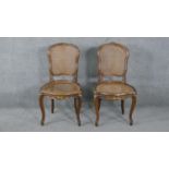 A pair of French style walnut salon chairs with carved and gilded decoration on cabriole supports.