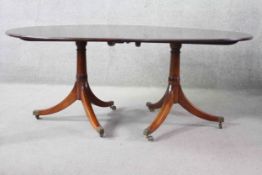 A Georgian style figured mahogany dining table with extra leaf on swept tripod pedestal supports.