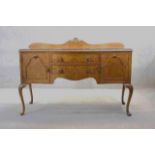 A mid century burr walnut Epstein sideboard with central drawers flanked by cupboards on carved
