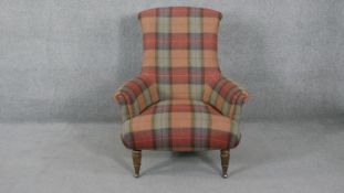 A Victorian style armchair in tartan upholstery on turned tapering supports terminating in brass