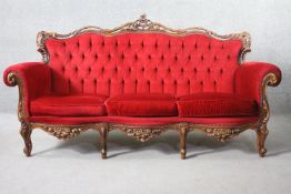 A carved foliate walnut framed Italian style sofa in deep buttoned velour upholstery.