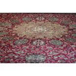 A large Wilton carpet with repeating floral medallions and trailing foliate decoration on a burgundy