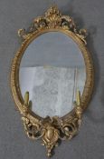 A 19th century girandole the oval plate in gilt gesso foliate decorated frame with twin candle