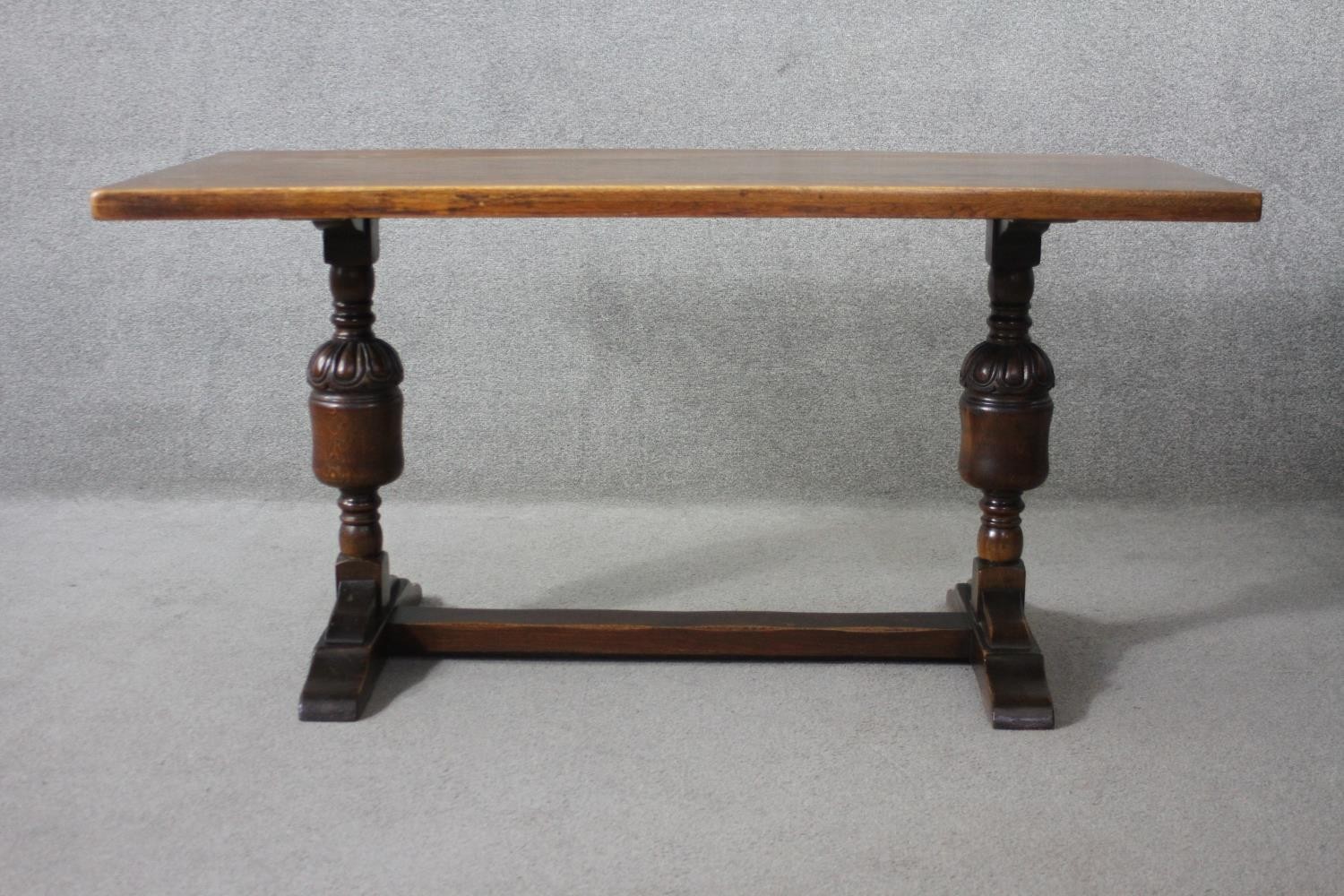 A mid century oak Jacobean style refectory dining table on carved baluster stretchered platform