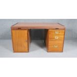A mid century teak pedestal desk with pull out slides and inset brass military style handles,